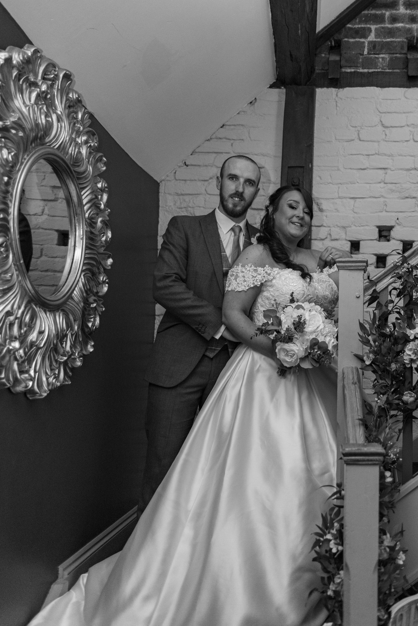 Bride and Groom posed on the staircase from ceremony room at The Barns Hotel Cannock