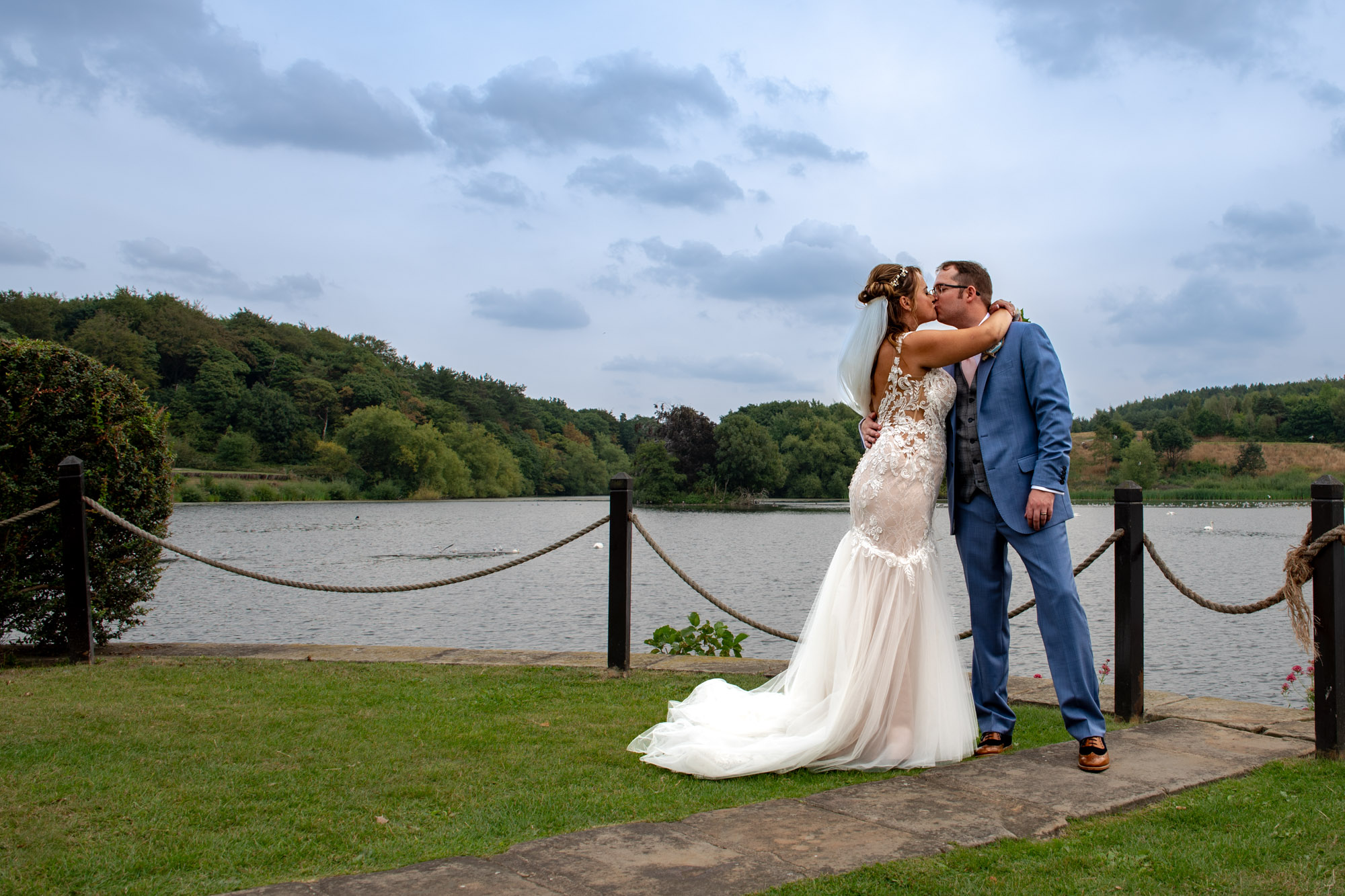 Bride and groom posed at lakeside at Waterton Park Hotel in Wakefield