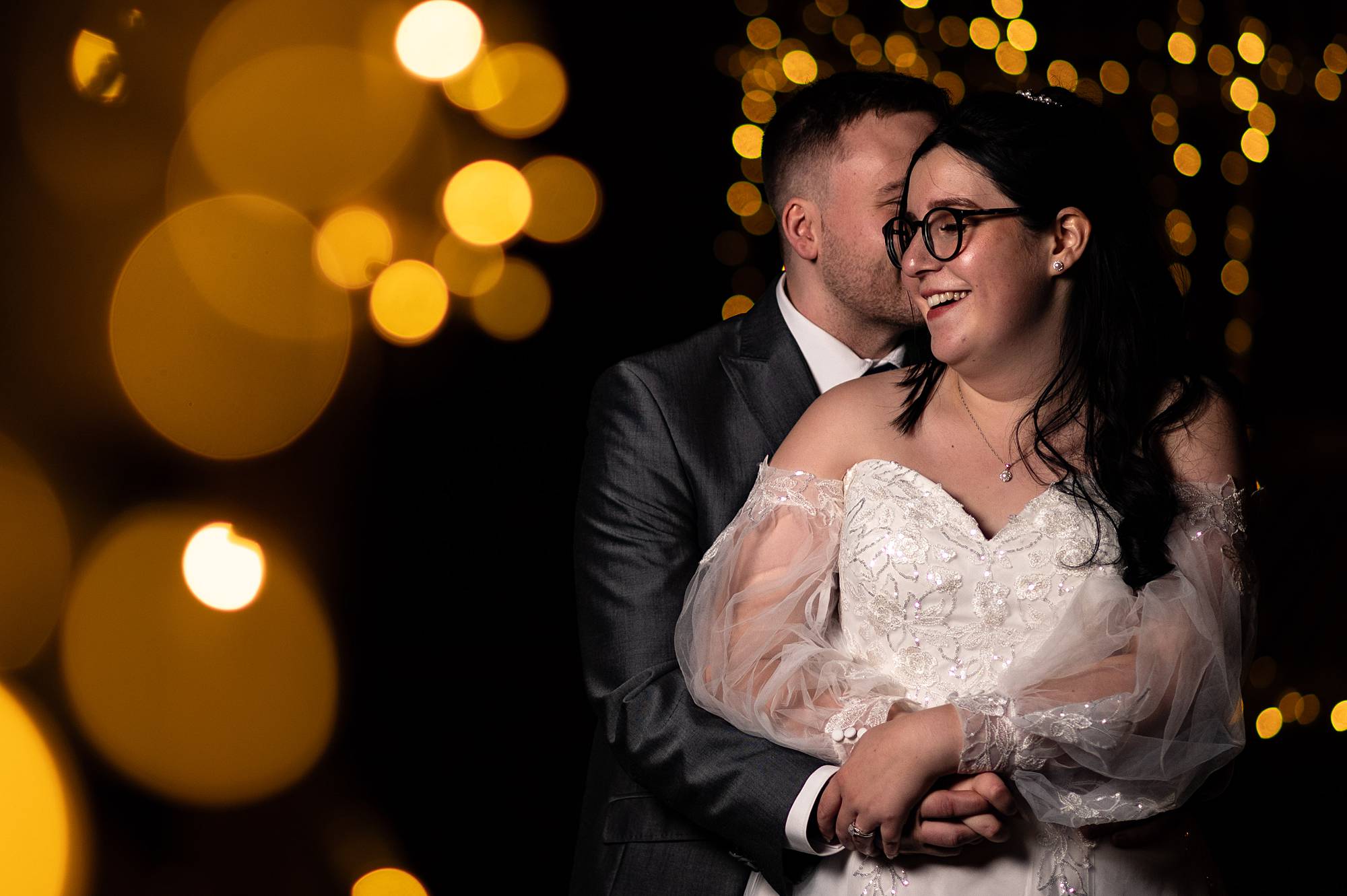 Creative portrait of a newly-wed couple at their wedding. Image was taken after dark with fairy lights nearby. Taken at Oak Farm Hotel in Cannock.